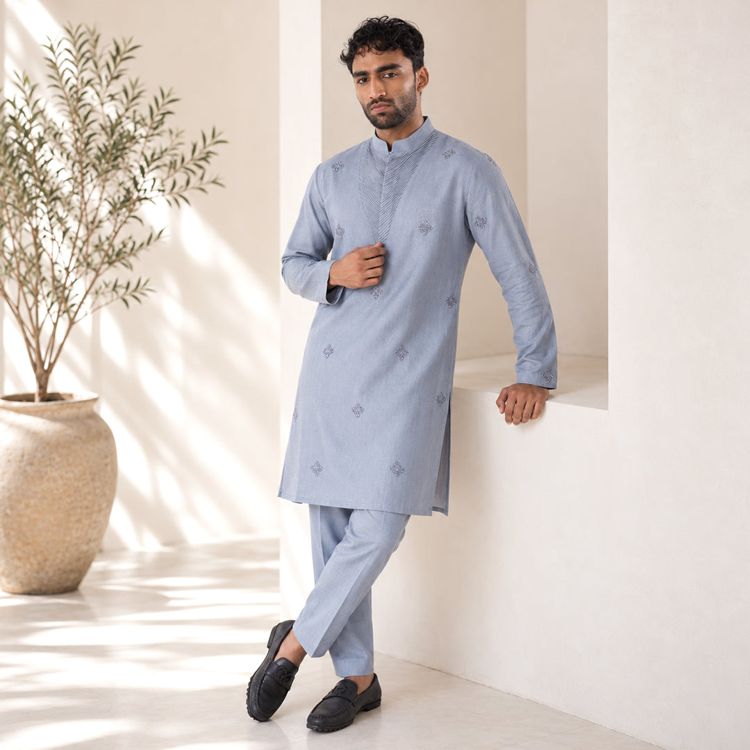 Airforce Blue Chevron-Bib Hemp Kurta Set in tonal blue, model leaning in an ivory set with an olive tree
