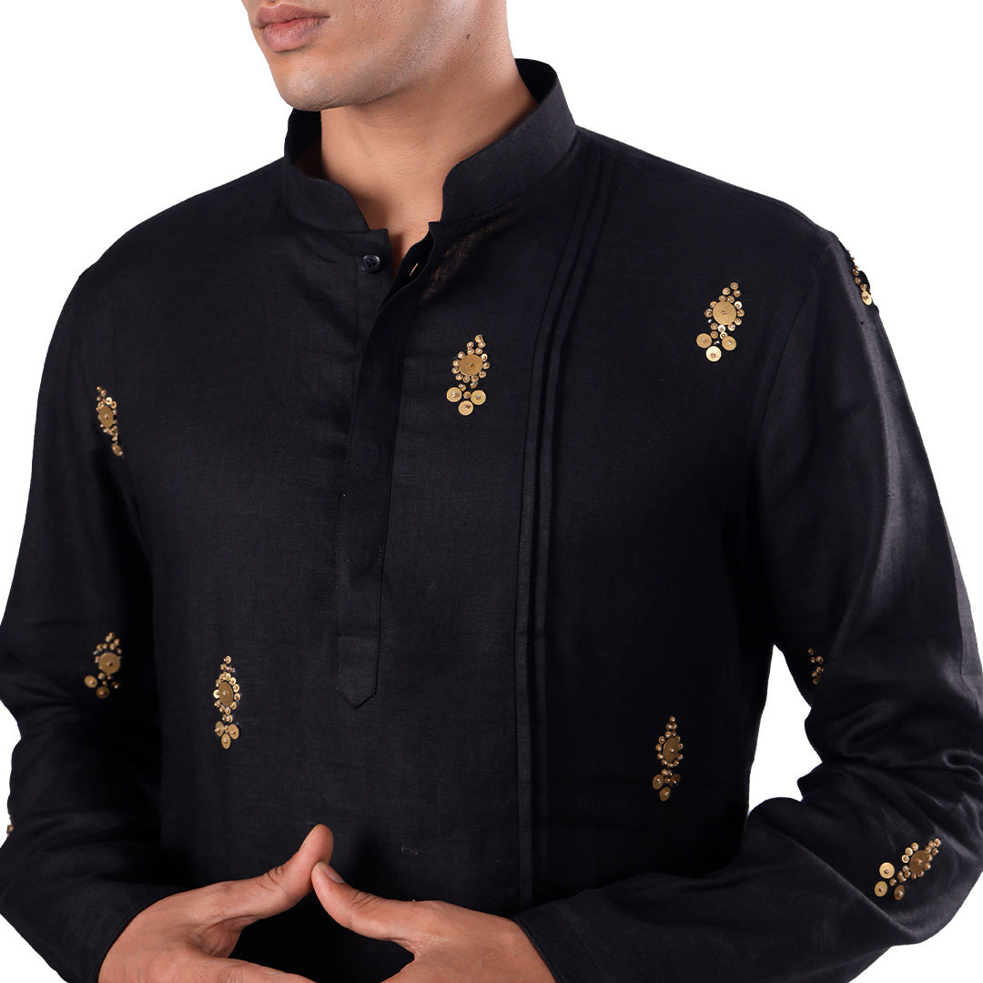 Macro detail of the black hemp kurta: pintucked placket and gold-toned embroidered motifs