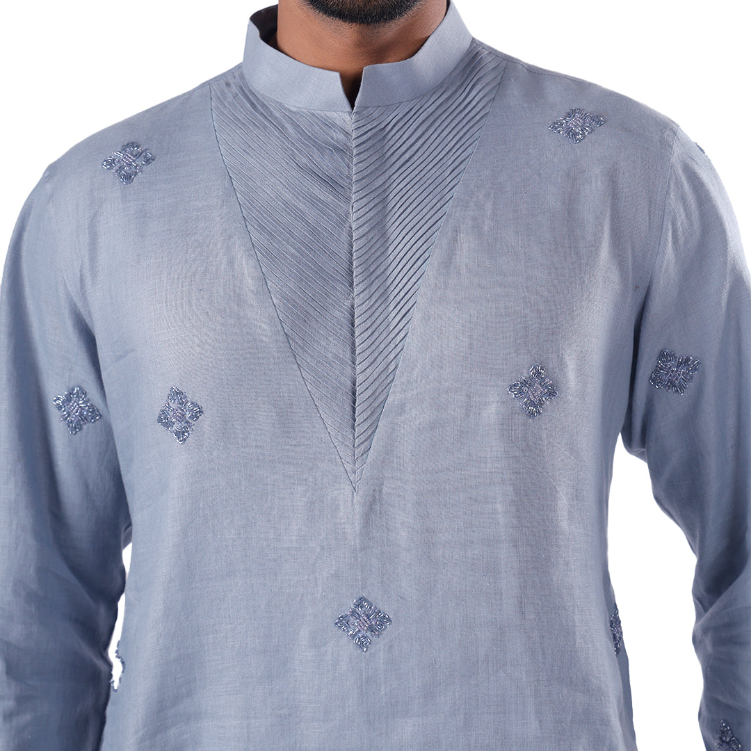 Close view of the airforce blue kurta chest showing diagonal pleats and embroidered motifs