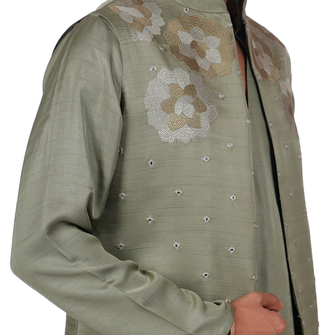 Macro detail of the sage Nehru jacket shoulder: floral embroidery with scattered mirrors
