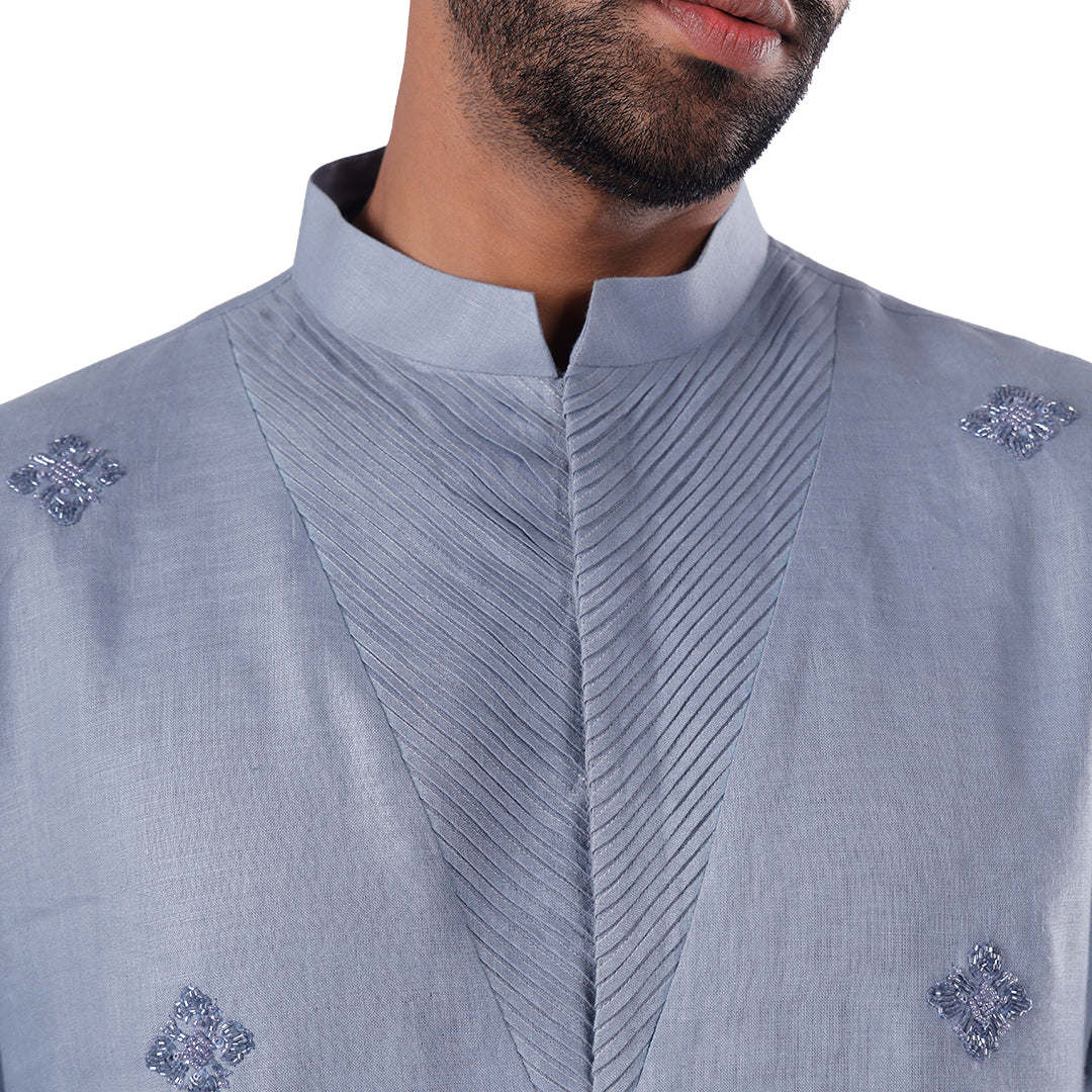 Macro detail of the blue kurta stand collar and chevron-pleated bib with silver-toned motifs