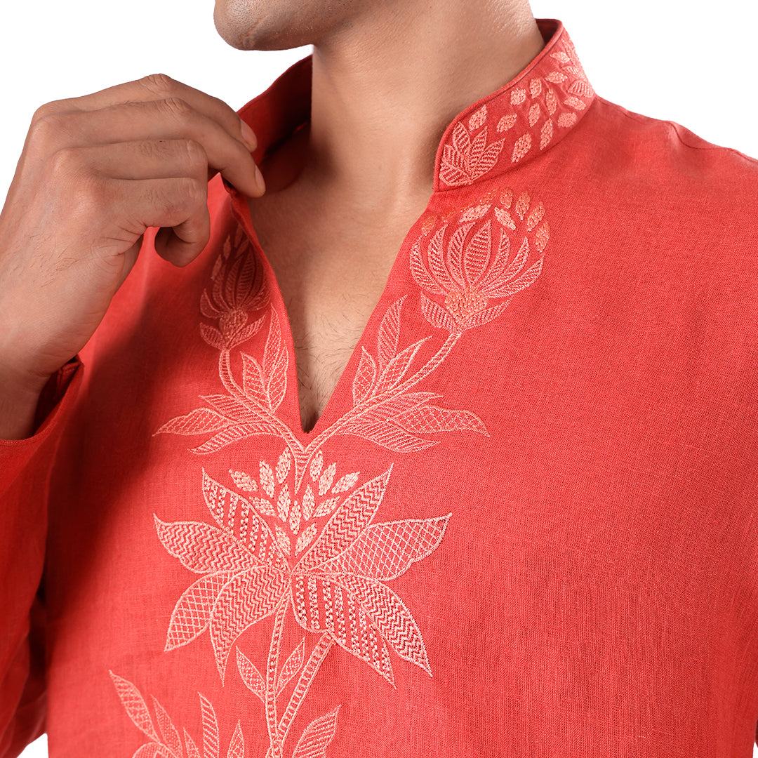 Macro detail of the coral kurta neckline: tonal botanical embroidery and open band collar