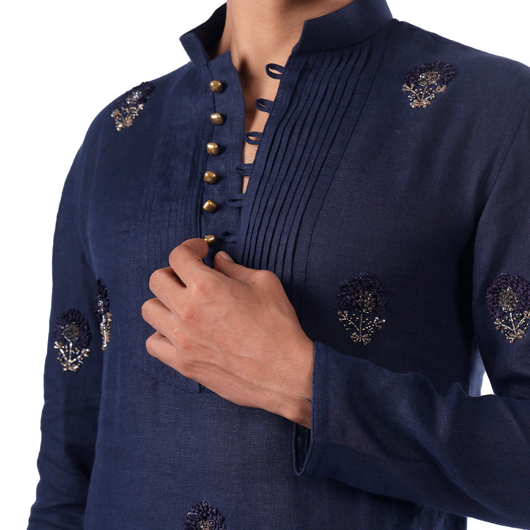 Macro detail of the indigo kurta: pintucked bib, metallic buttons and silver-toned floral motifs