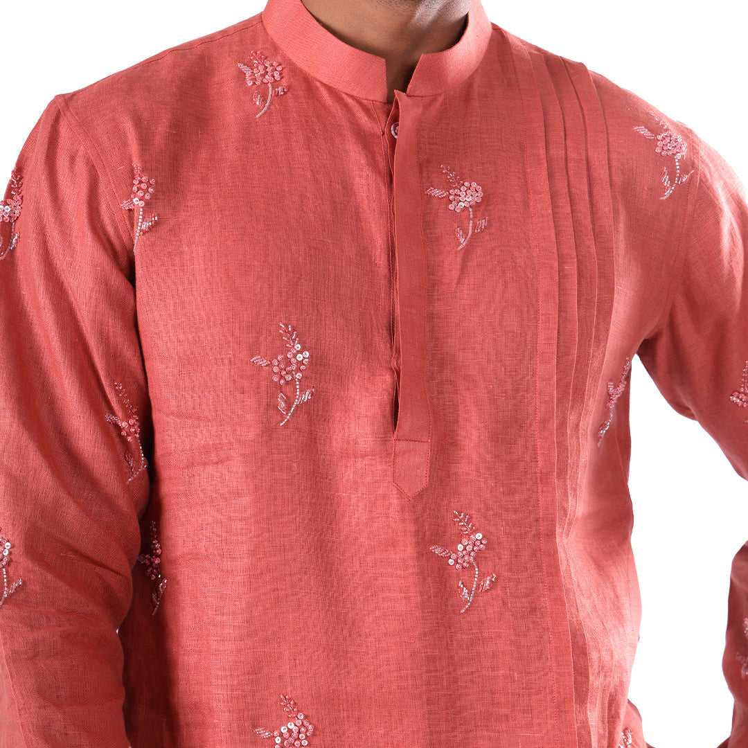 Macro detail of the rosewood hemp kurta: embroidered floral sprigs and vertical pleats beside the placket
